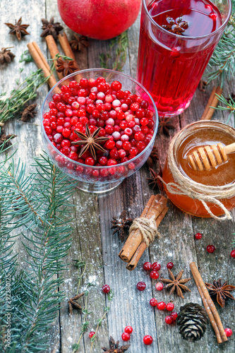 Warm cranberry tea with honey and pomegranate. Wood background.