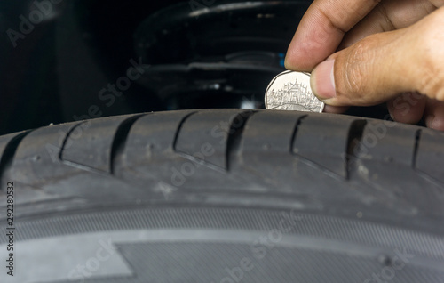 Fotografi Man place a penny into tread grooves across the tire for checking tire tread dep
