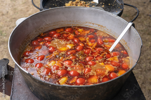 Red tomato soup in cauldron for sell in street food market, Ukraine, closeup
