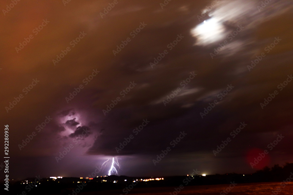 Lightening strike with blurred movement fast clouds and moon light