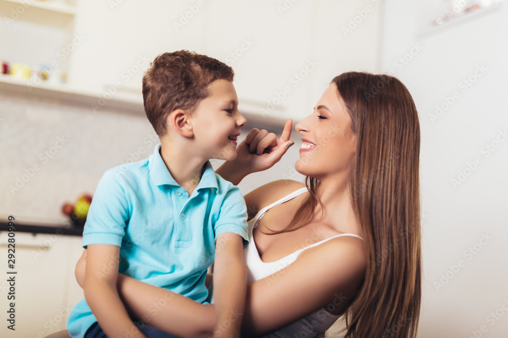 Happy family mother and child son hugging in kitchen Happy family mother and child son hugging in kitchen