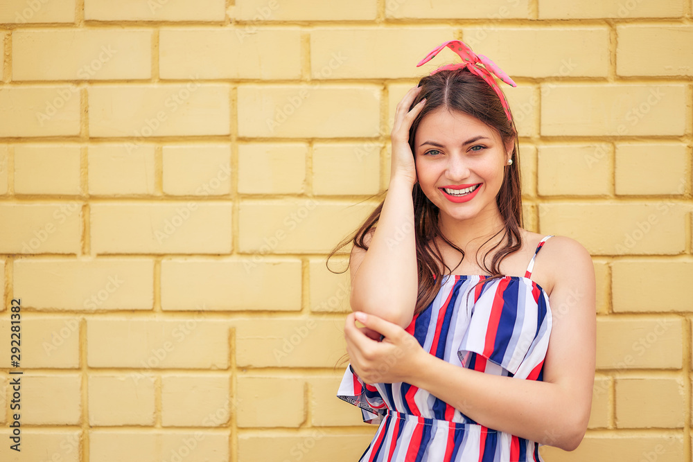 close-up young woman with a pink bow emotionally fun posing on a background of a yellow brick wall. copy space close-up young woman with a pink bow emotionally fun posing on a background of a yellow brick wall. copy space