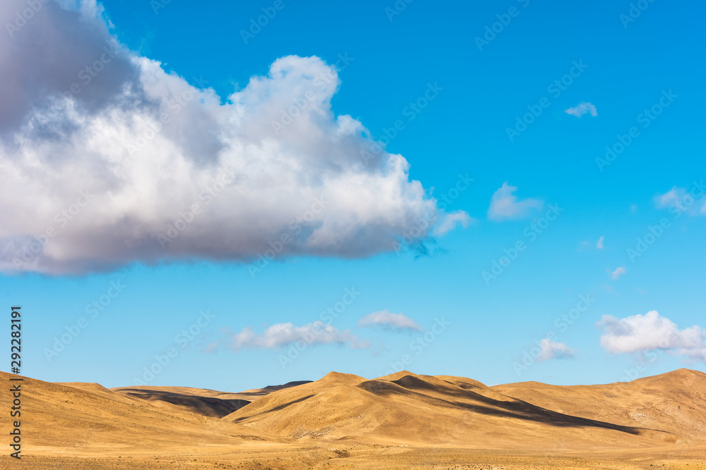 Clouds on a blue sky over mountains with dried yellow grass Clouds on a blue sky over mountains with dried yellow grass