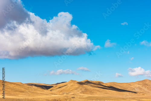 Clouds on a blue sky over mountains with dried yellow grass