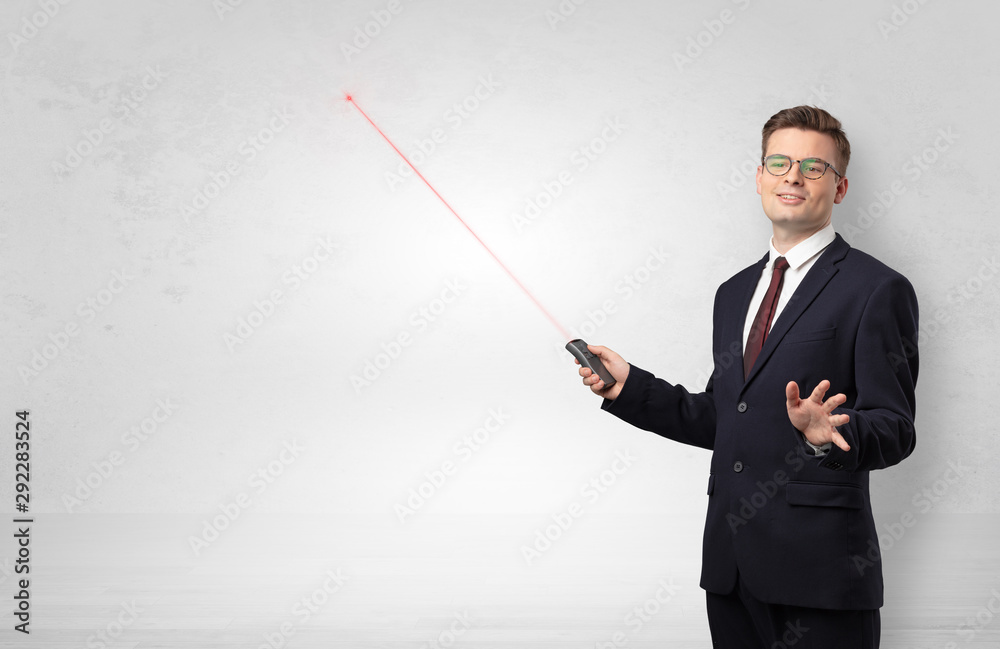 Young businessman with laser pointer and copyspace white wall