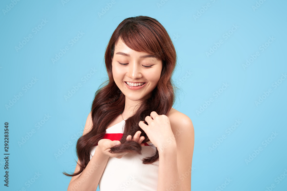 Asian woman smiling with long hair, isolated over blue background. Asian woman smiling with long hair, isolated over blue background.