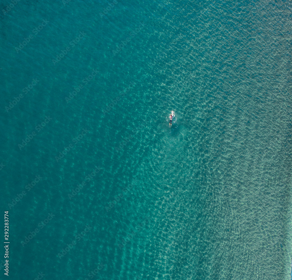 Swimmer in an empty ocean/sea enjoying a summer morning sunrise. Aerial of a man/women swimming Swimmer in an empty ocean/sea enjoying a summer morning sunrise. Aerial of a man/women swimming