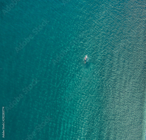 Swimmer in an empty ocean/sea enjoying a summer morning sunrise. Aerial of a man/women swimming 
