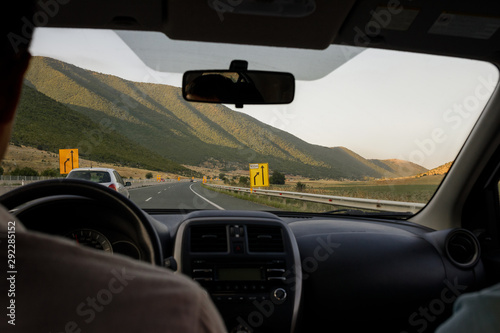 inside view of the car on the road in summer. Man drives a car in mountains
