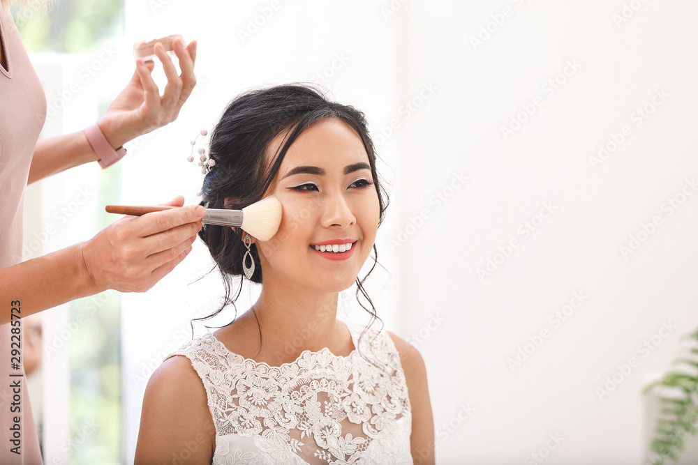 Professional makeup artist working with young Asian bride at home Professional makeup artist working with young Asian bride at home
