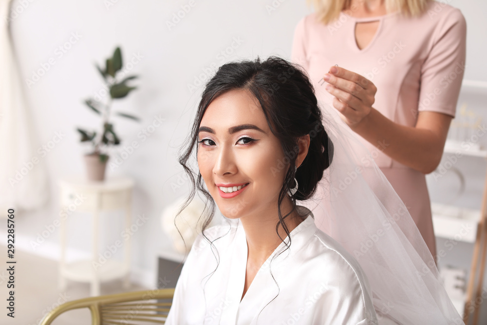 Fototapeta premium Professional hairdresser working with young Asian bride at home