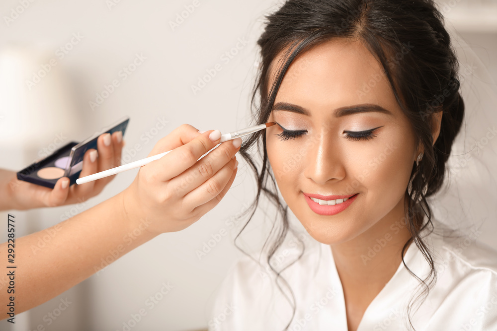 Professional makeup artist working with young Asian bride at home Professional makeup artist working with young Asian bride at home