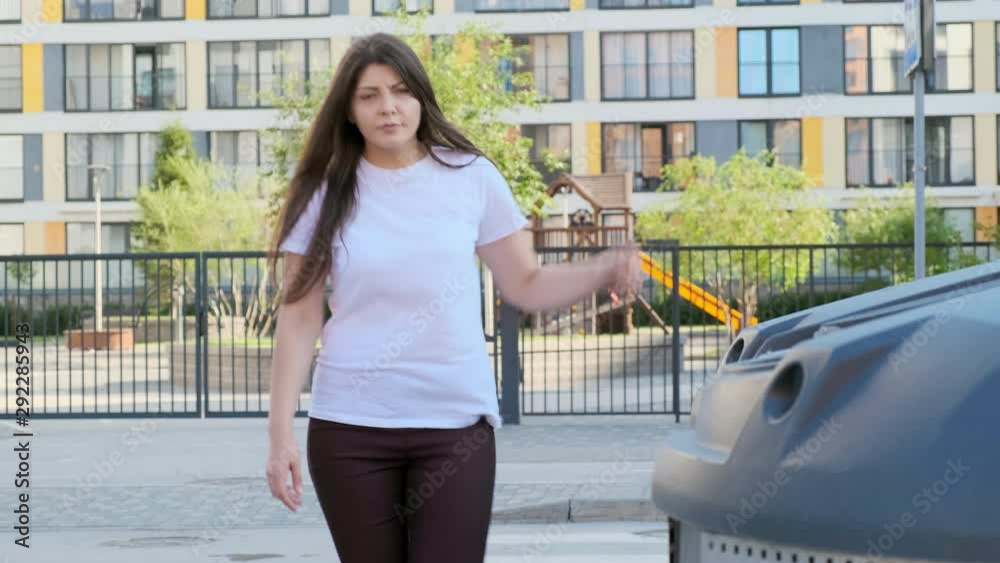 Young woman throws a bag of garbage into the tank near the house. Young woman throws a bag of garbage into the tank near the house.