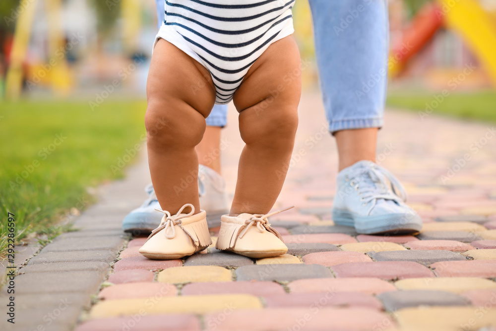 Cute little baby learning to walk outdoors - obrazy, fototapety, plakaty 