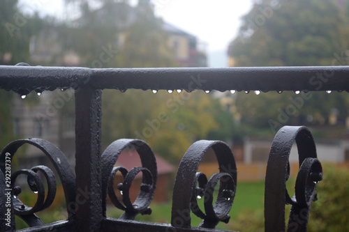 Drops of water on the railing of the balcony in rainy weather against the backdrop of city streets.