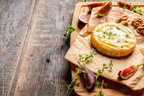 Baked camembert cheese with figs, walnuts, honey and thyme on the rustc background. Selective focus. Shallow depth of field. photo