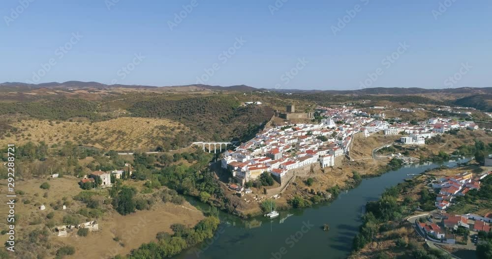 Aerial view of the town of Mertola in southeastern Portuguese Alentejo destination region, located in the margin of Guadiana River, whit its medieval castle, located on the highest point. Portugal. Aerial view of the town of Mertola in southeastern Portuguese Alentejo destination region, located in the margin of Guadiana River, whit its medieval castle, located on the highest point. Portugal.