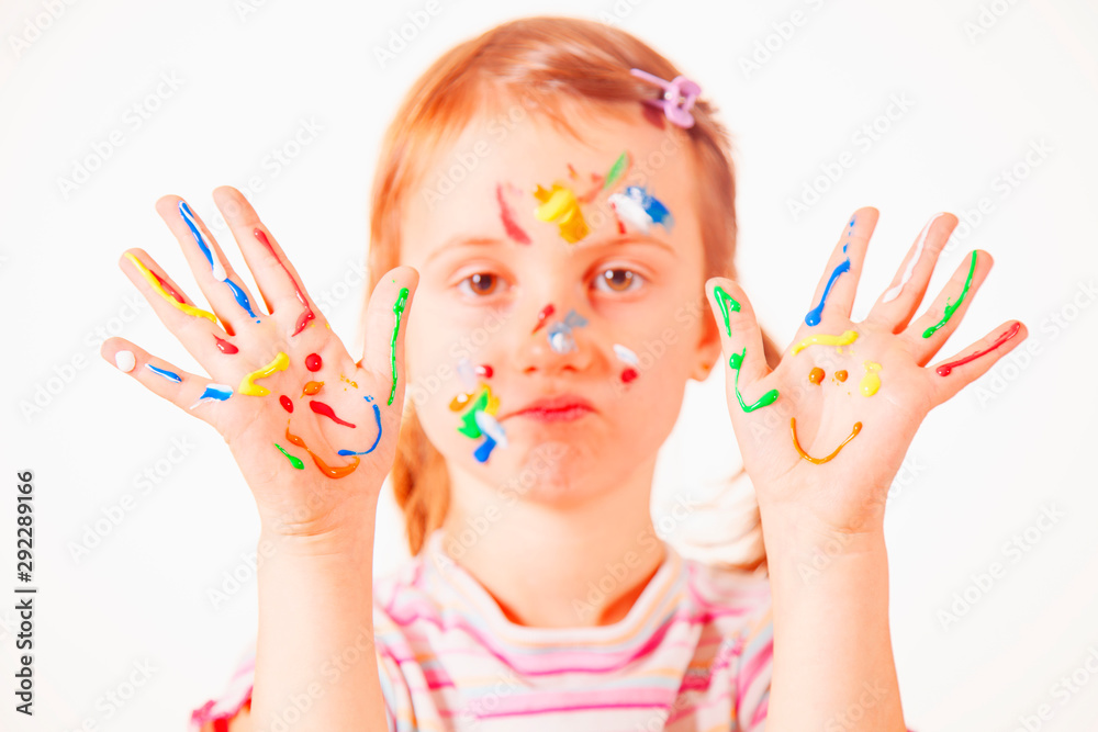 Children's make up. Humorous portrait of young girl with colorful painted hands and face. Selective focus on hands. Children's make up. Humorous portrait of young girl with colorful painted hands and face. Selective focus on hands.