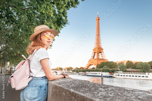 Happy asian woman student with backpack observing view of the Eiffel Tower in Paris. Travel and education in France concept © EdNurg