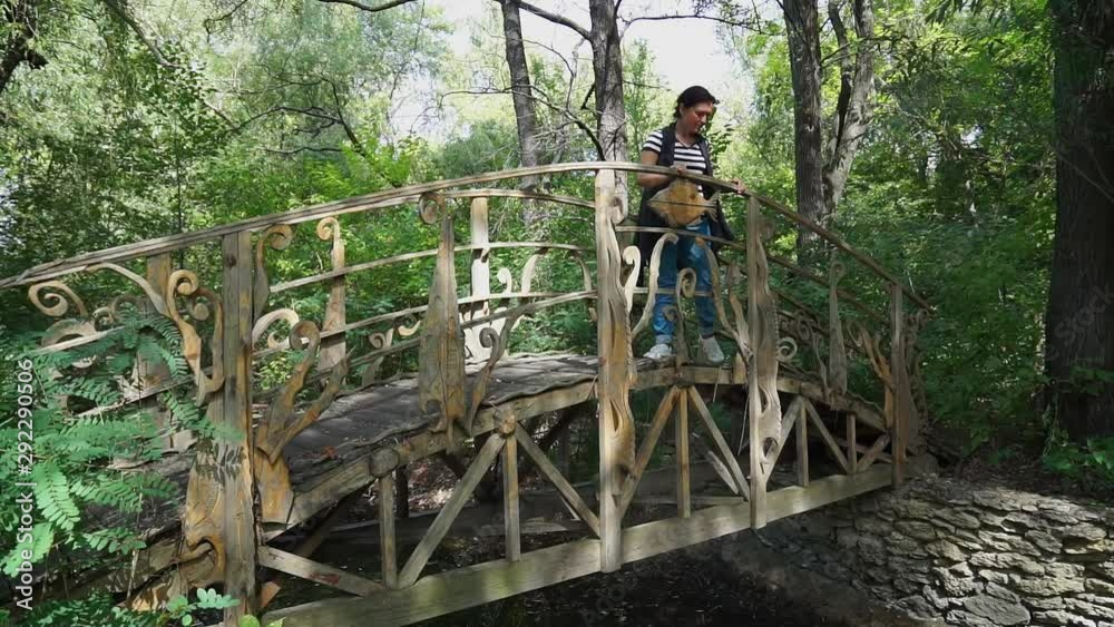 Young aucasian woman having a calm relaxing walk on wooden bridge in park Young aucasian woman having a calm relaxing walk on wooden bridge in park