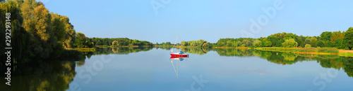 Water of an autumn lake  panoramic view  reflection in calm water. Motor boat with sail