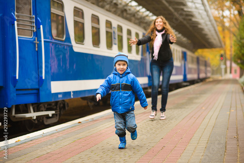 Mom catches up with laughing runaway little son along blue train at station © cheese78