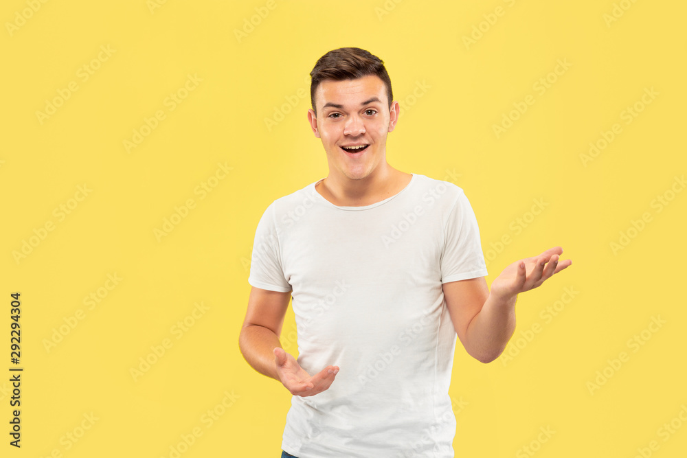 Caucasian young man's half-length portrait on yellow studio background. Beautiful male model in shirt. Concept of human emotions, facial expression, sales, ad. Pointing and showing something. Caucasian young man's half-length portrait on yellow studio background. Beautiful male model in shirt. Concept of human emotions, facial expression, sales, ad. Pointing and showing something.