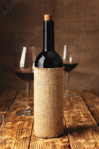 A bottle of wine on the background of glasses in the cellar of the winery.