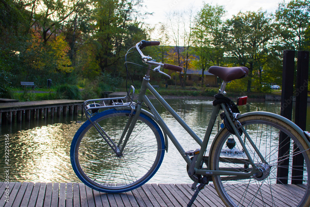 Ghent, Belgium; 10/31/2018: Classic comfort bike parked in a dock in front of a lake in a park