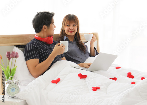 Young Asian couple having coffee in bed