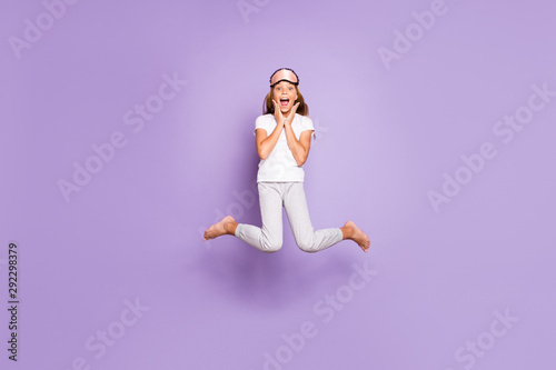 Full size photo of impressed beautiful excited blonde hair model kid wakeup hear wonderful morning news scream wow omg jump high wear white t-shirt pants isolated over violet purple color background