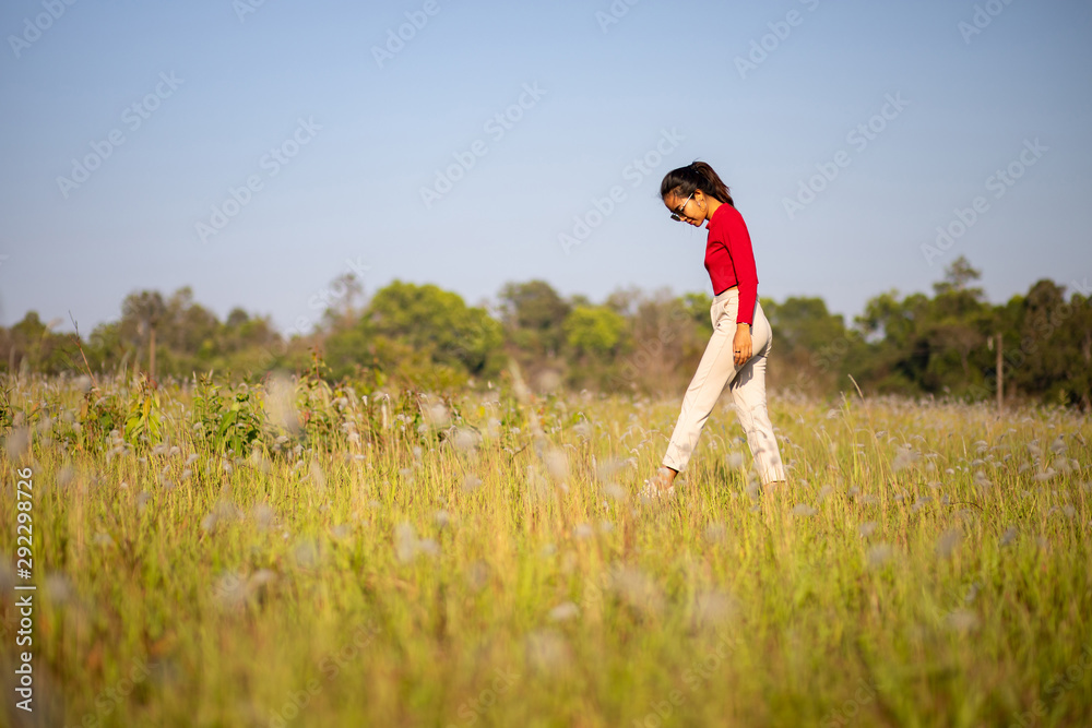 Hipster Asian woman in red and sunglasses on white flower and grass field Hipster Asian woman in red and sunglasses on white flower and grass field