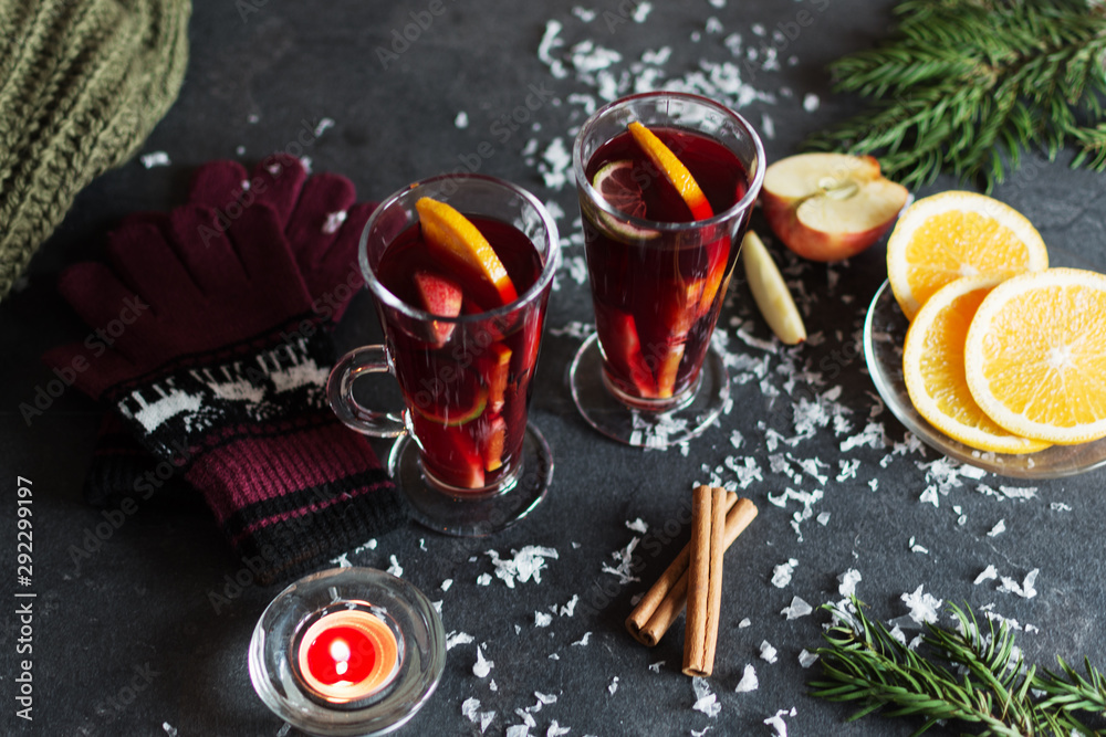 Mulled wine with slice of orange, apples and spices on christmas background with different decorations. Hot christmas drink.