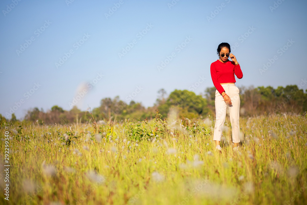 Hipster Asian woman in red and sunglasses on white flower and grass field Hipster Asian woman in red and sunglasses on white flower and grass field