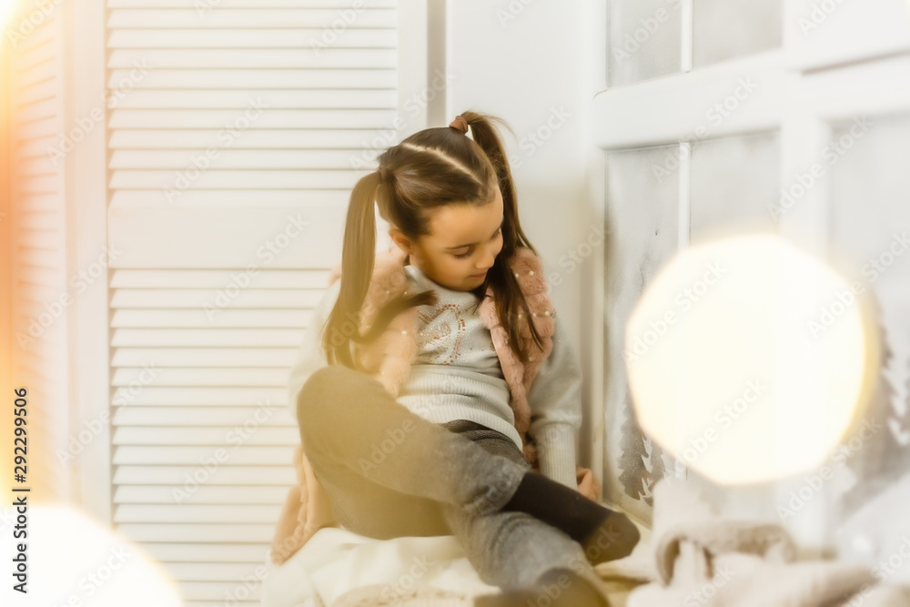 little girl sitting by the window in the children's room little girl sitting by the window in the children's room