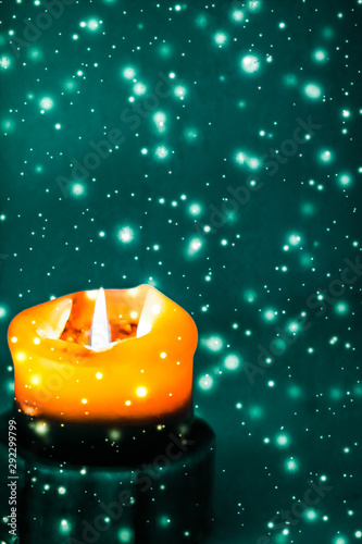 Canvas Print Orange holiday candle on green sparkling snowing background, luxury branding des