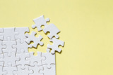 Jigsaw puzzle white piece on yellow backdrop