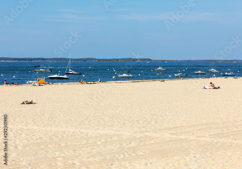 People are enjoying a sunny day on a sandy beach in Arcachon, France