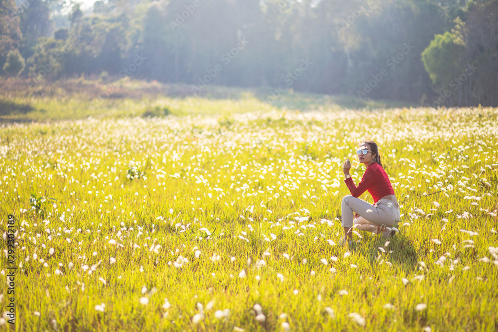 Hipster Asian woman in red and sunglasses on white flower and grass field Hipster Asian woman in red and sunglasses on white flower and grass field