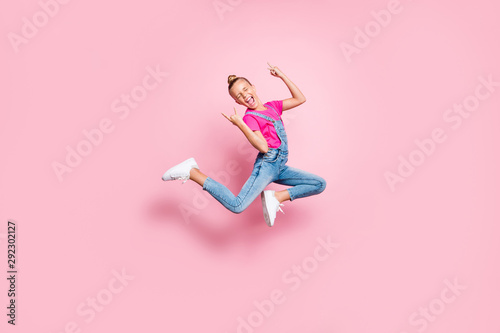Full length body size photo stylish trendy cute cheerful rejoicing girl wearing jeans denim overall t-shirt fuchsia jumping showing rock sign isolated over pink pastel color background