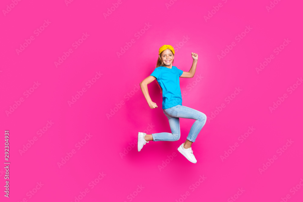 Full size photo of positive cheerful kid jump run have fun enjoy spring holiday discounts wear blue denim jeans clothes sneakers isolated over pink color background