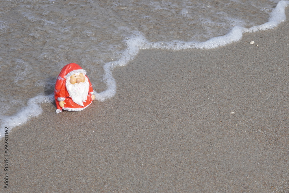 Christmas by the sea. Little garden gnome in Santa Claus costume goes on vacation in the tropics and takes a san bath (Not copyrighted) Christmas by the sea. Little garden gnome in Santa Claus costume goes on vacation in the tropics and takes a san bath (Not copyrighted)