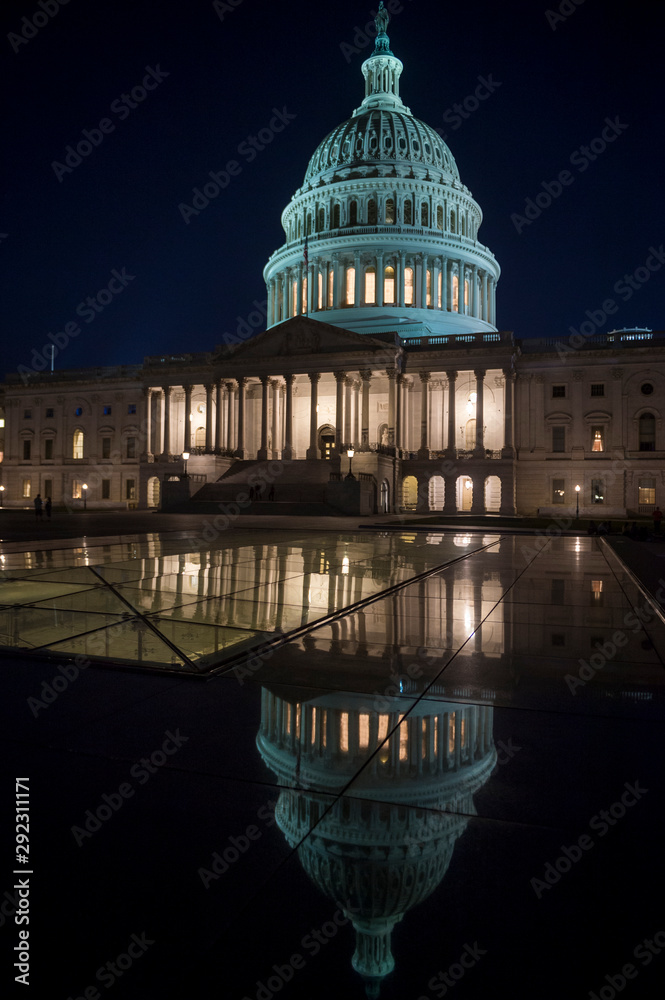 Fototapeta premium Scenic evening view of the glowing lights of the US Capitol Building with detail reflecting under night sky in Washington DC, USA
