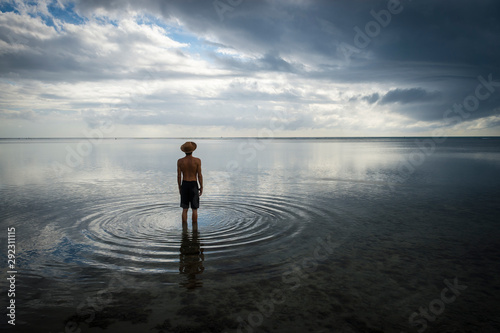 фотографія Tropical silhouette of man in straw hat standing in calm shallow waters with rip