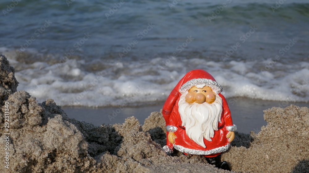 Christmas by the sea. Little garden gnome in Santa Claus costume goes on vacation in the tropics Christmas by the sea. Little garden gnome in Santa Claus costume goes on vacation in the tropics