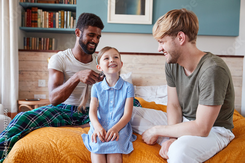 Same Sex Male Couple At Home Getting Daughter Ready For School Plaiting Her Hair photo