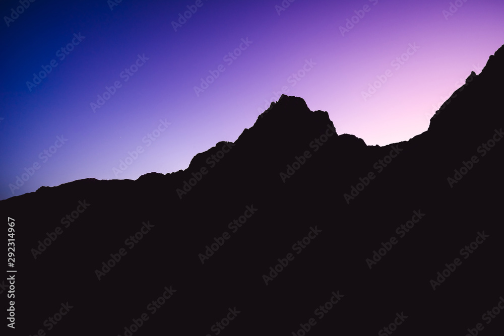 Dreamy photo of a dusk or dawn of mountain alpine landscape. Blue and purple sky above a mountain horizon. Silhouette of a summit or peak of a mountain. Spitzmauer, Totes Gebirge, Austria.