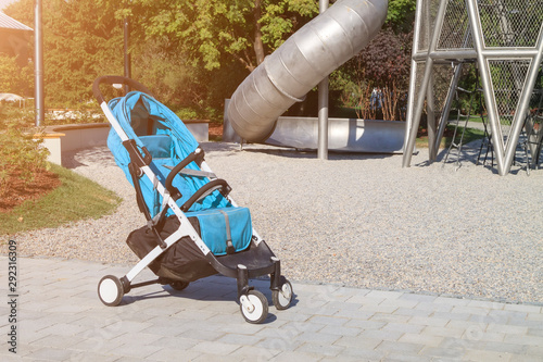 empty stroller stands near modern playground with large metal slide