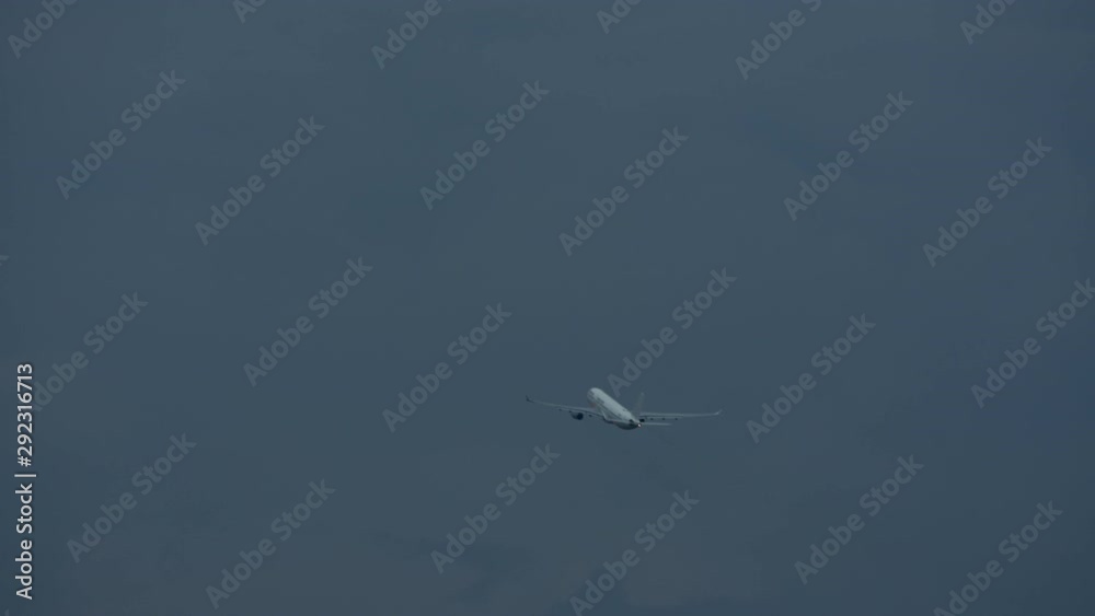 A white aircraft flying away in a grey morning sky A white aircraft flying away in a grey morning sky