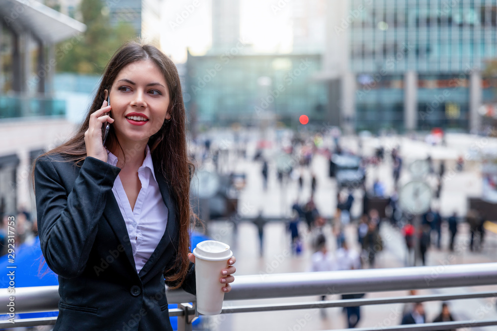 Junge Geschäftsfrau mit Telefon und Kaffee in der Hand vor modernen Bürogebäuden und Menschen auf der Straße Junge Geschäftsfrau mit Telefon und Kaffee in der Hand vor modernen Bürogebäuden und Menschen auf der Straße